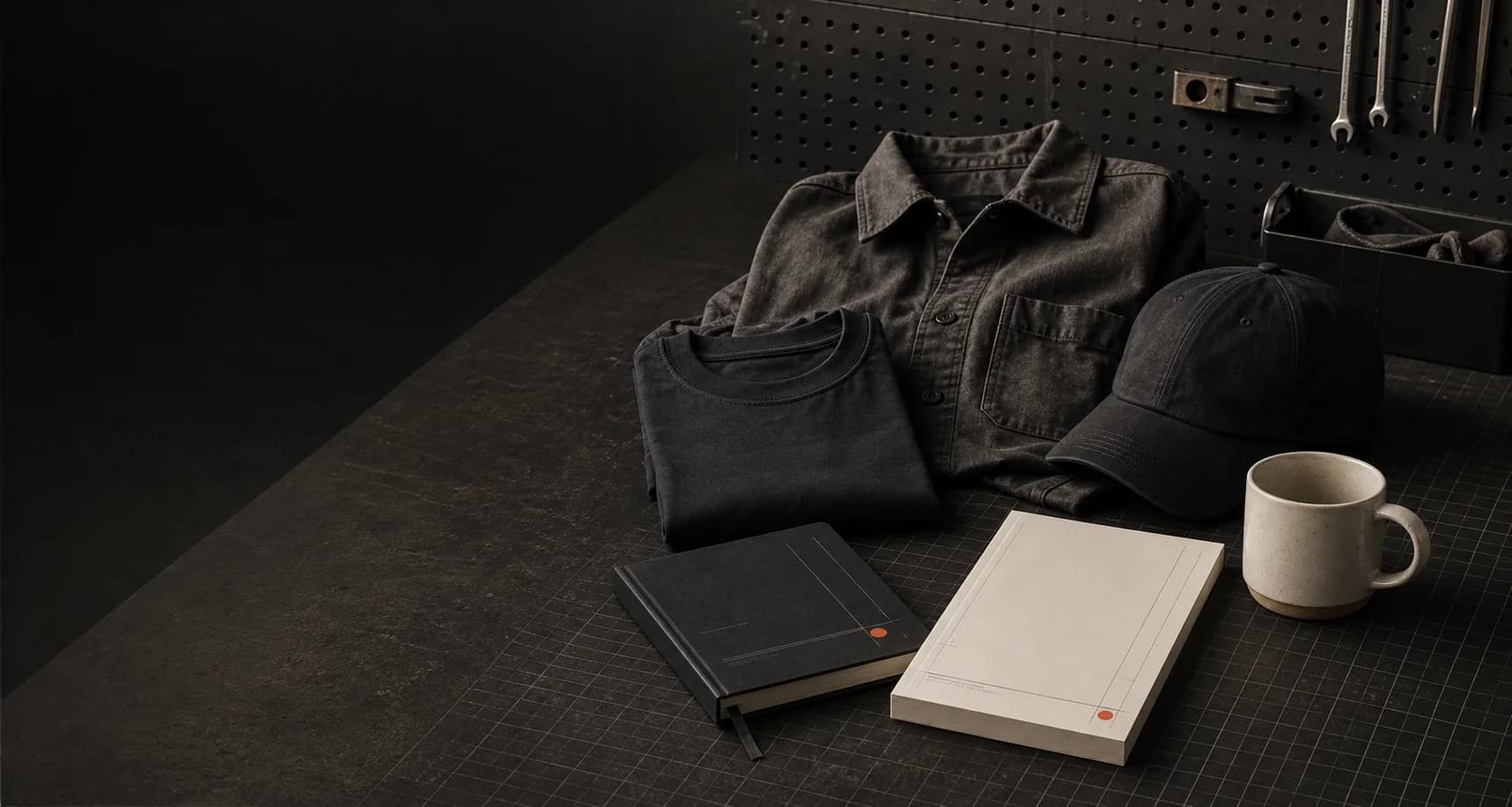 Illustrative campaign concept showing workwear, a field book, desk pad, cap, and mug on a dark operator workbench